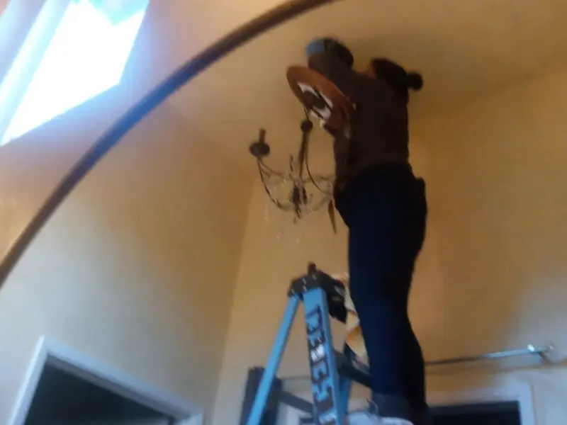 Electrician installing a chandelier in a Handy residence